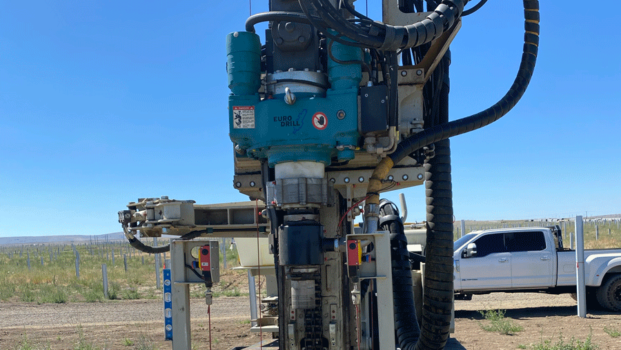 Comacchio MC 22 drill rig front view showing the Eurodrill rotary head, mast, and clamp system aligning on casing in an open field jobsite.