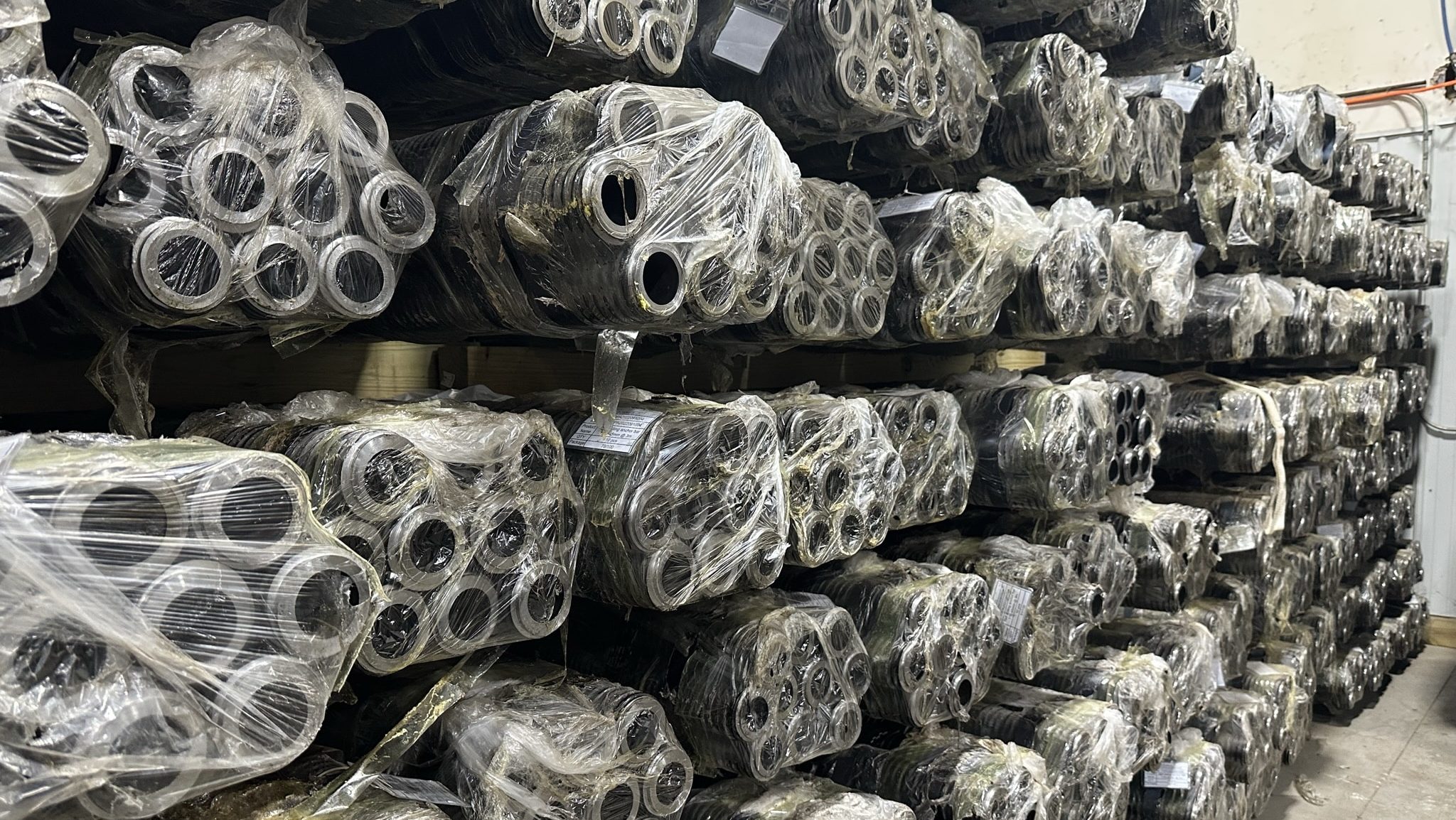 Bundles of hollow bar micropile tubing wrapped in plastic and stacked in inventory racks at National Piling Products.
