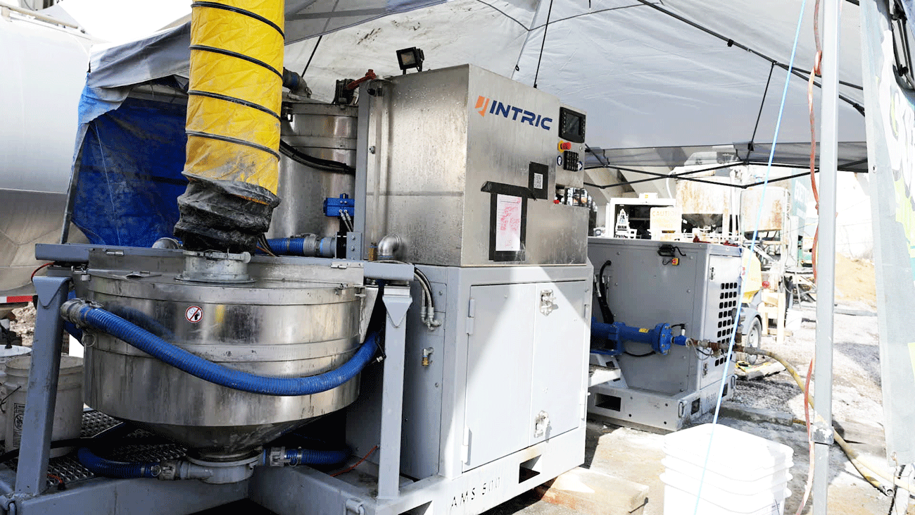 Made in the USA Intric AMS500 fully automated mixing station with 125 gallon high-shear mixing tank, 330 gallon storage tank, and diesel power pack set up on jobsite, available for rent or purchase from National Piling Products