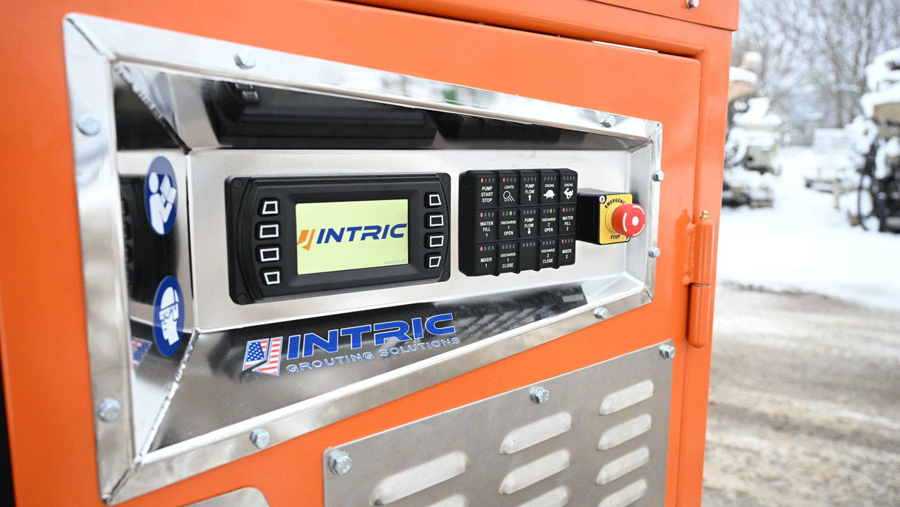 Intric D9 grout plant main control panel with digital display, function switches, and emergency stop button on orange enclosure