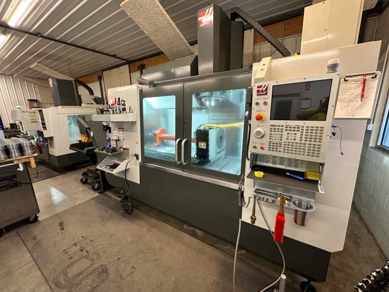 Haas VF‑4 CNC machining center inside National Piling Products’ shop actively machining custom drill string tooling components behind safety glass.