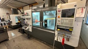 Haas VF‑4 CNC machining center inside National Piling Products’ shop actively machining custom drill string tooling components behind safety glass.