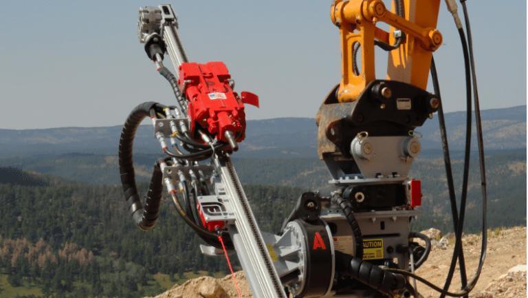 TEI HEM hydraulic excavator‑mount drilling attachment positioned over a steep hillside, ready for micropile and anchor drilling on a remote geotechnical project.