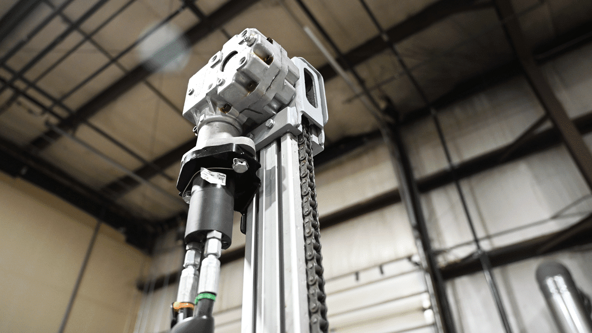 Close-up of the American-made TEI MP260 man-portable drilling system chain feed mast head and hydraulic drive assembly, showing rugged components for limited-access drilling