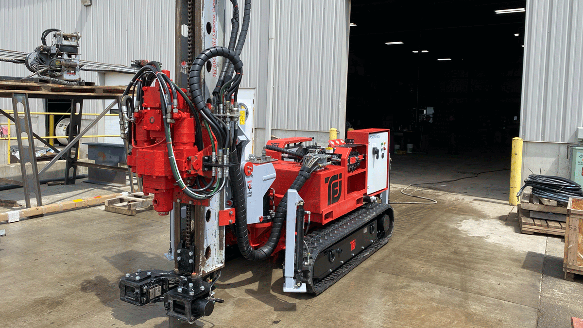 TEI TD‑100 electric‑hydraulic limited‑access drill rig positioned outside a shop with mast and clamp system ready for mobilization.