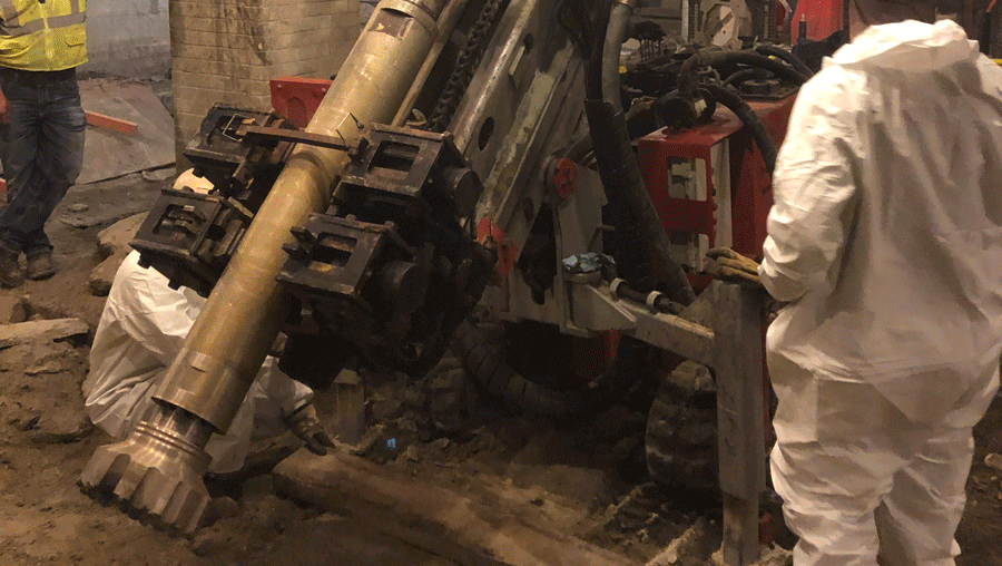 “TEI TD‑75 electric‑hydraulic limited‑access drill rig drilling interior micropiles with clamp engaged on casing inside an existing building.”